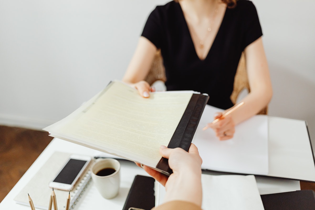 Woman handing paperwork to another person